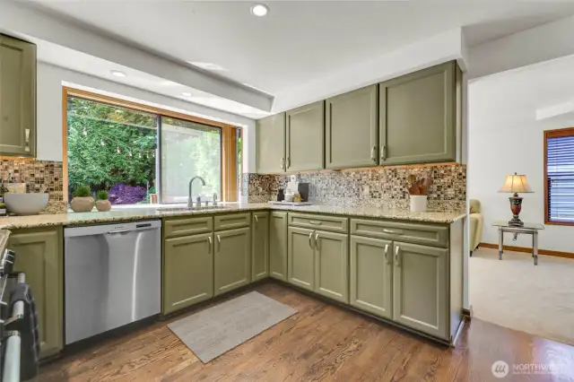 Renovated kitchen with oak hardwood floors, granite counters and tile backsplash. Large windows provide lovely backyard views.
