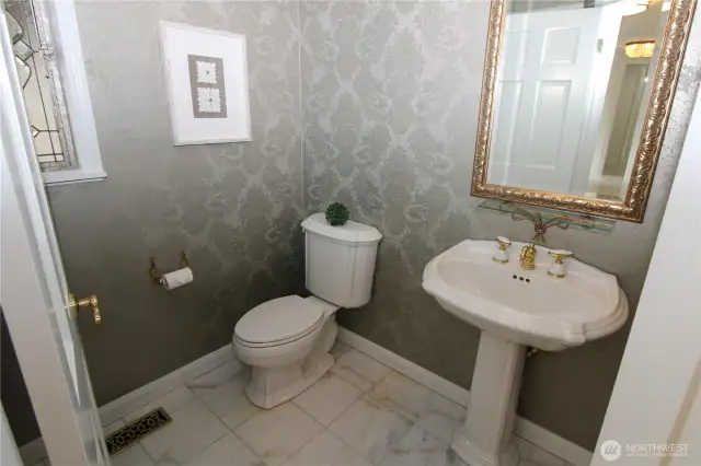 Feel pampered in this exquisite half bath with marble floors and gold touches, conveniently located near the front entrance