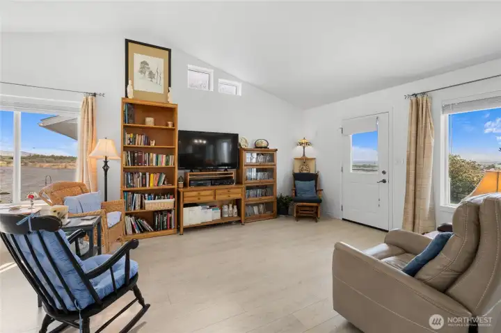 Living room with vaulted ceilings and TONS of natural light, also beautiful laminate flooring.