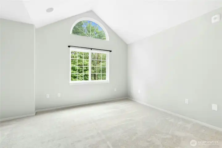 Primary bedroom featuring vaulted ceilings, an arched window, and abundant natural light. Primary bedroom featuring vaulted ceilings, an arched window, and abundant natural light.