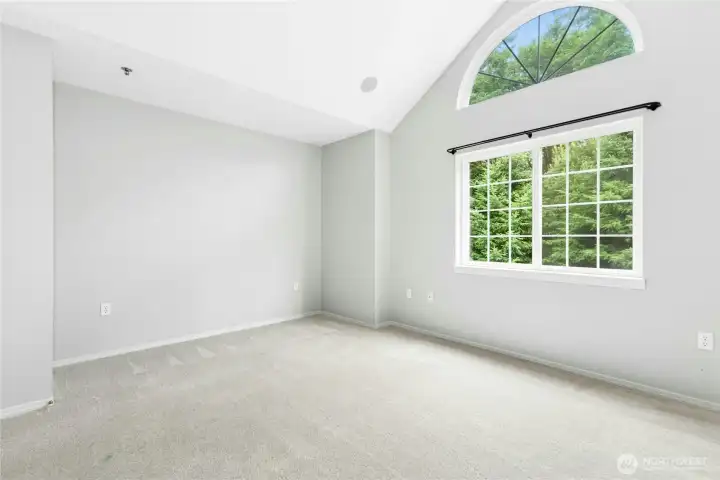 Primary bedroom with vaulted ceilings, large arched window, and abundant natural light. Primary bedroom with vaulted ceilings, large arched window, and abundant natural light.