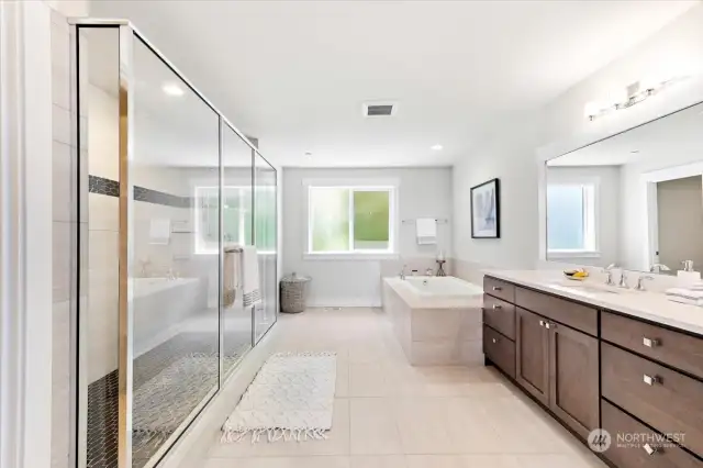 Luxurious primary bath with heated floors, a dual sink vanity, soaking tub, and a large separate shower.