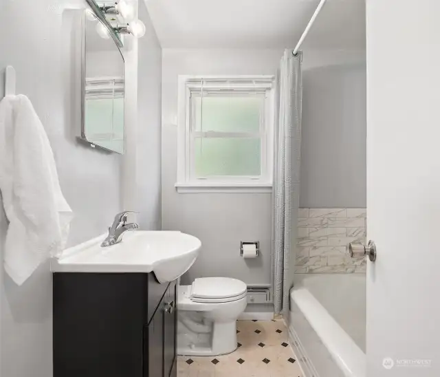 Updated bathroom (done in 2018) has newer tiles, floor, vanity, sink, and tub.