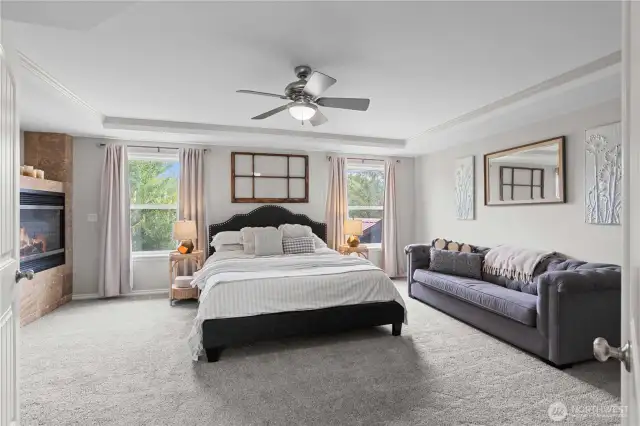 Spacious primary suite is elegant and features large windows that flood the room with great light. The trayed ceiling adds a touch of sophistications and height to the space. An attached, luxurious five-piece bath offers a perfect sanctuary for relaxation, featuring a spa like feel. A beautiful double sided fireplace is positioned between the bedroom and the bathroom, providing warmth and ambiance, making it an ideal spot to unwind and enjoy peaceful moments