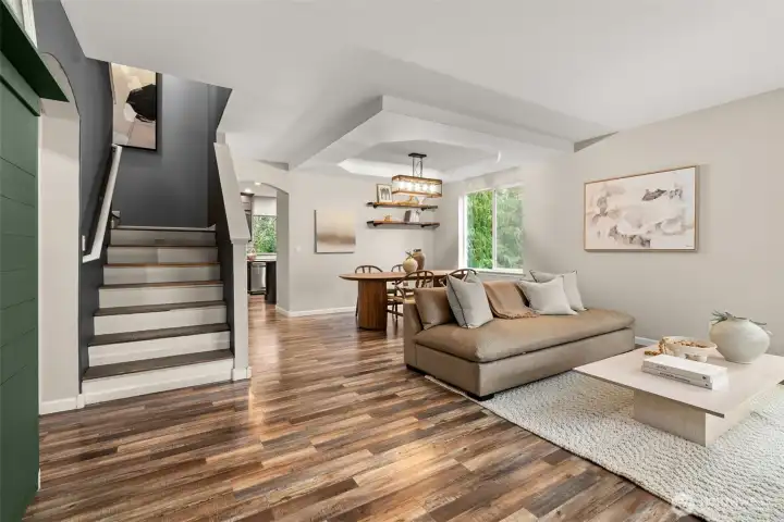 Beautifully updated open-concept living and dining area featuring warm wood-style flooring, abundant natural light, and a modern designer aesthetic. The spacious layout includes a cozy living room with custom lighting, a stylish dining nook, and easy flow to the kitchen. Fresh paint, clean lines, and contemporary finishes make this space perfect for relaxing or entertaining.