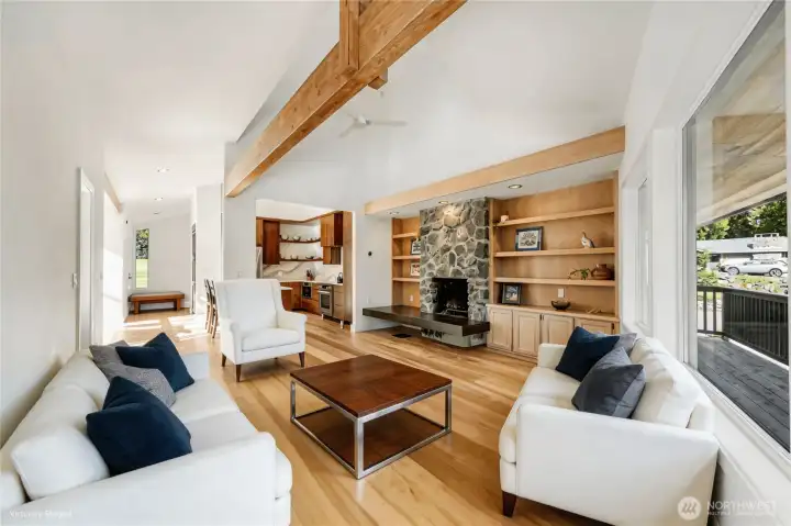 A look at the main living space, with the quarry rock fireplace w/polished cement hearth anchoring this beautiful room. Newly stained beams, built-in cabinets and shelving, and deck access add to this beautiful space.