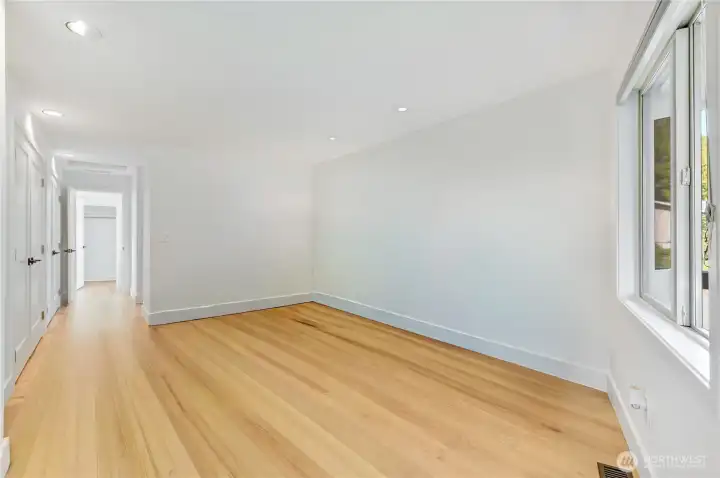 Same view as the last photo of the main level primary bedroom space un-staged. There's a door to the right that leads to the covered patio, and on the left is a row of closets with new doors.