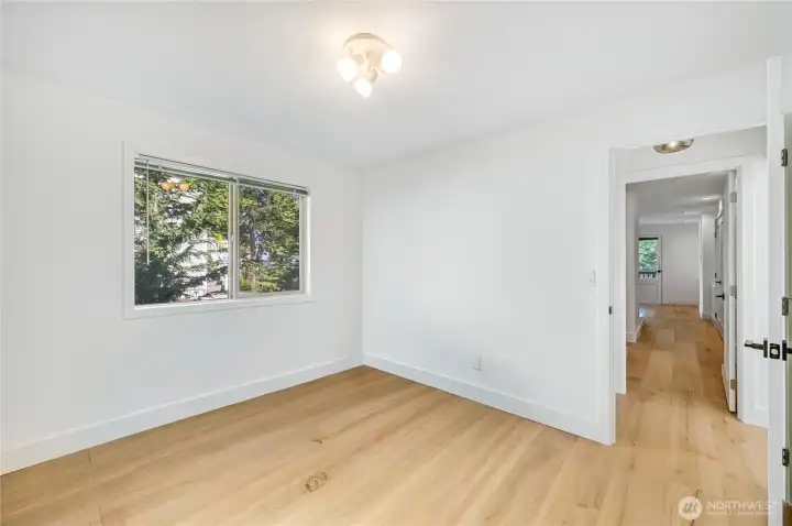 The main level guest bedroom has a quarter bath just outside the door.  The view in the background looks into the primary bedroom.  Sellers use this room as their den.