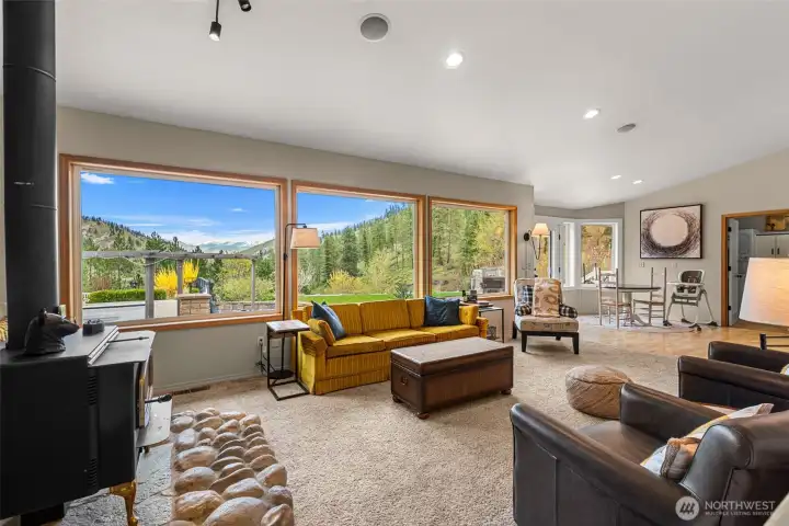 View-filled living room with picture windows and wood stove centerpiece