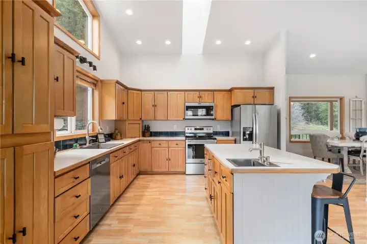 Warm, inviting kitchen with rich wood cabinetry, generous counter space, and a central island—designed for both everyday living and entertaining, all under soaring ceilings and abundant natural light.