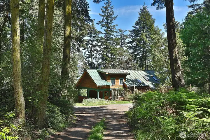 Your arrival. There is a circular driveway. The unfinished shop is beyond the right edge of this photo. The path/stairs to the beach are to the left of the front porch.