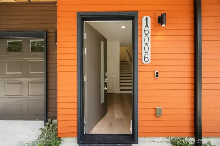 A welcoming modern entry featuring a vibrant, contemporary front door paired with durable, high-end vertical siding.