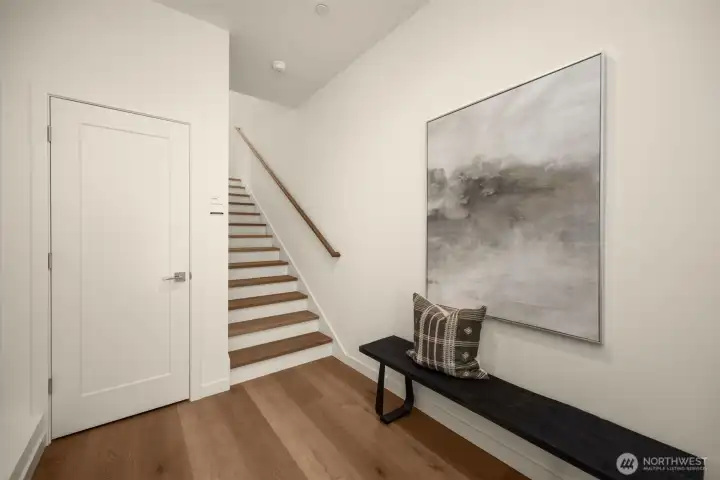 Step inside to an airy foyer showcasing a floating architectural staircase, clean minimalist lines, and an immediate sense of luxury.