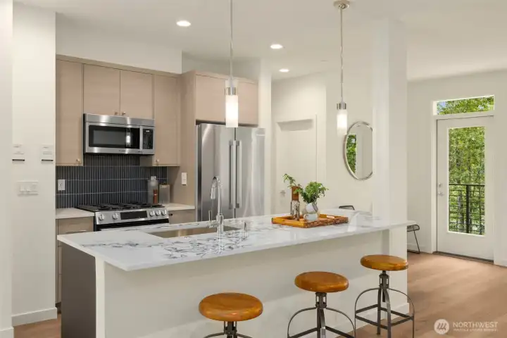 The kitchen boasts a massive quartz-topped waterfall island, premium stainless steel appliances, and custom flat-panel cabinetry.