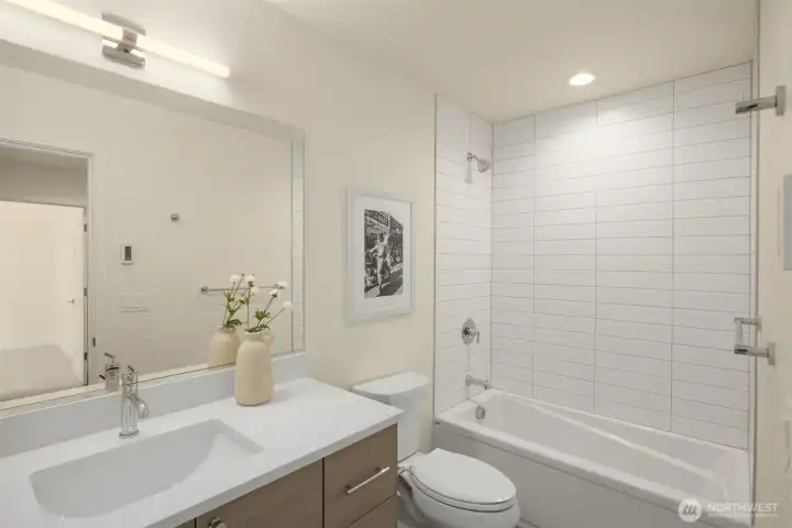 Additional upper-level bathroom matching the home's high-end aesthetic with a clean white vanity, contemporary lighting, and custom vertical stacked tilework.