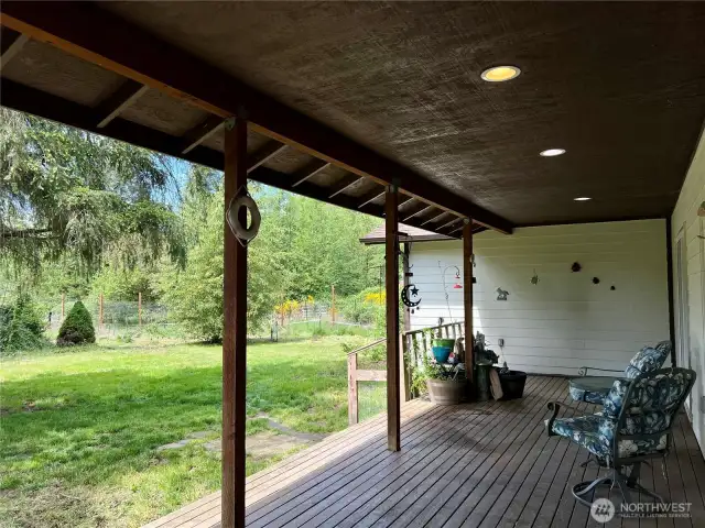 This photo captures the peaceful view from the front patio, looking out over the property’s expansive acreage. Imagine sipping your morning coffee while taking in the open space, mature trees, and natural beauty right from your doorstep.
