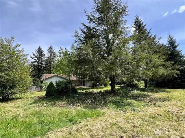 A distant view from the acreage looking back toward the front of the home showcases the property’s spacious setting and welcoming exterior. The home sits gracefully on the landscape, offering a sense of privacy and connection to the surrounding land.