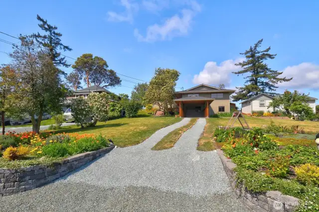 The entry is framed by beautiful gardens with raspberries, straberries, flowers and vegetables.