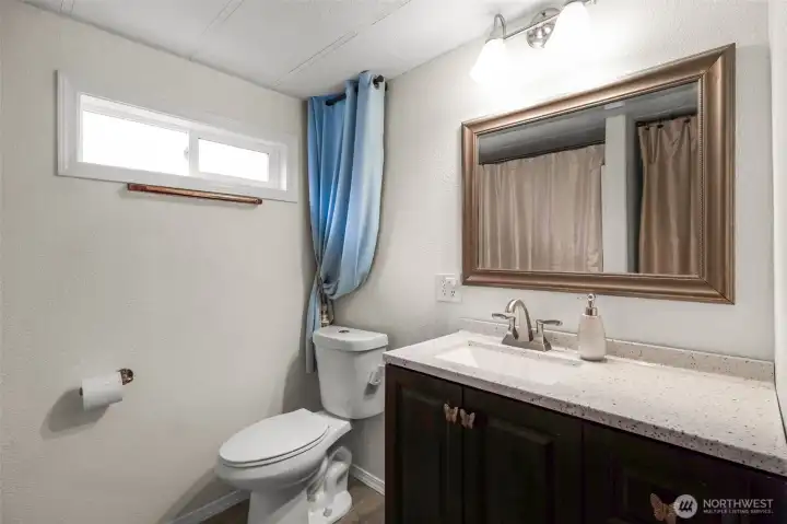 The bathroom has a nice sized vanity, a shower and storage space behind the door.