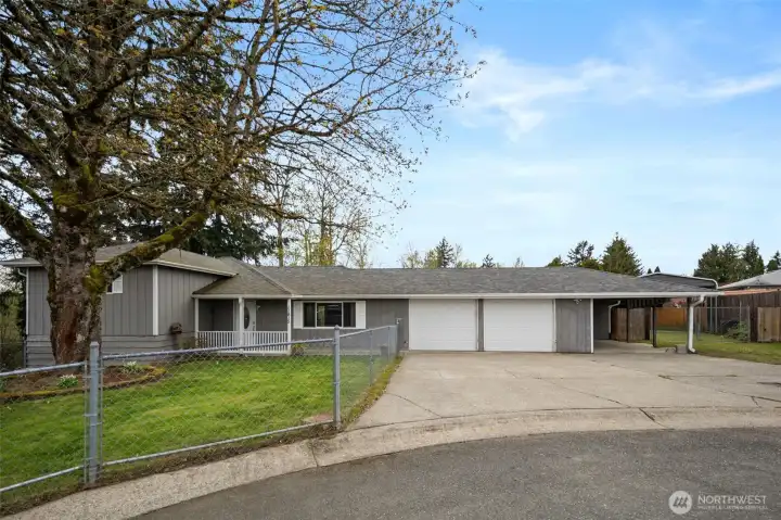 Front of the home with a fenced front yard, 2 car garage and carport.