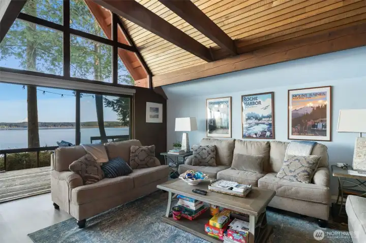 Living room with two large sliders to deck and 180 views of Case Inlet with Mt Rainier.  Open beams and wood-lined ceiling fits in with our wooded wonderland.