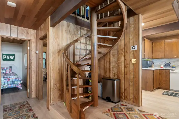 Centrally located spiral stairs with attitude.  Hallway to two main level bedrooms.  Full bath on left, Kitchen to right.