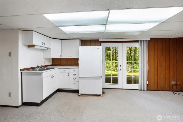 A sink, cabinetry, and  a refrigerator are all in the lower level bonus room.