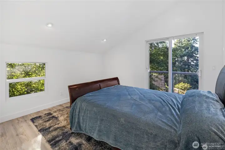 A bright bedroom with sliding glass doors opens to a private balcony, bringing fresh island air and peaceful evergreen views into the living space. A bright bedroom with sliding glass doors opens to a private balcony, bringing fresh island air and peaceful evergreen views into the living space.