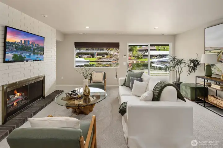 Downstairs, a relaxed, waterfront rec room made for movie nights, game days, and easy gatherings—where the fireplace adds warmth and the canal just beyond keeps the setting effortlessly connected to the outdoors.