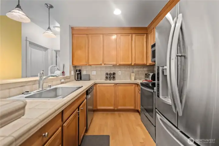 Functional kitchen with wood cabinets, tile counters, and ample workspace. Functional kitchen with wood cabinets, tile counters, and ample workspace.