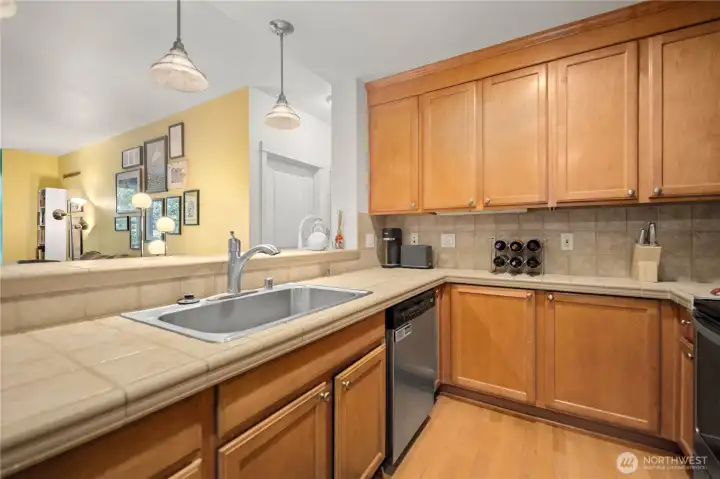 Functional kitchen with wood cabinets, tile counters, and ample workspace. Functional kitchen with wood cabinets, tile counters, and ample workspace.