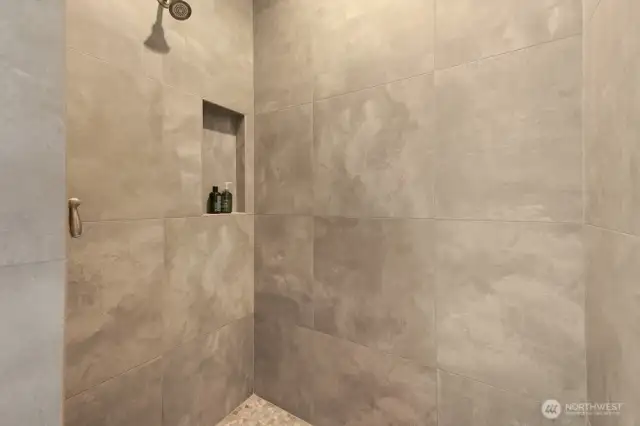 Hallway bathroom on the main floor features a custom, handmade vanity, walk in shower, and large format tiles on floor and shower.