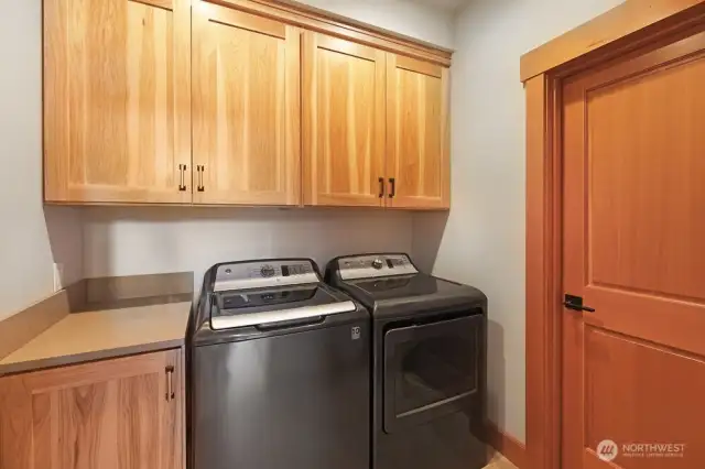 Laundry room with utility room in the back of the house with custom cabinetry and nearly new appliances.