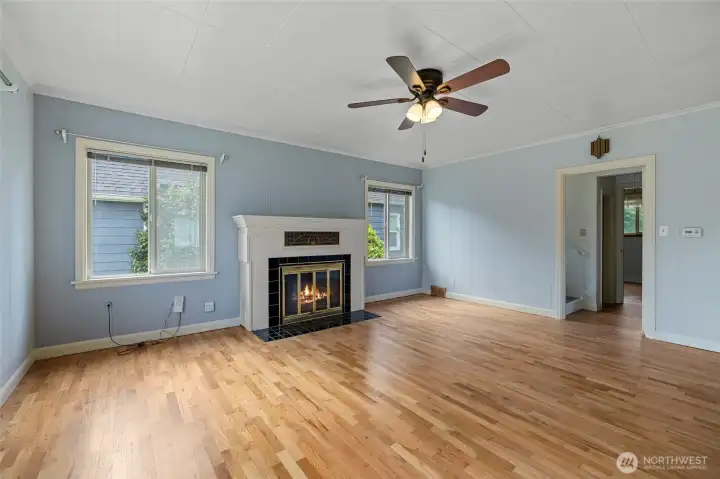 Spacious living area with oak flooring - flames in fireplace virtually staged