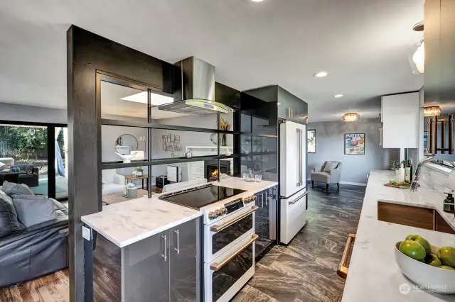 View of the kitchen with appliances. The living room is on the left of the kitchen and a den in the background.