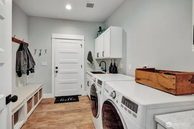 A well-appointed mudroom designed for effortless organization. Imagine kicking off your shoes and hanging up coats before entering the main house. This practical space features a conveniently located washer and dryer and sink making laundry a breeze.