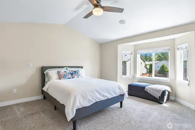 Primary bedroom with vaulted ceilings and bay window that overlooks the backyard.