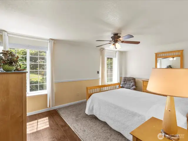 The primary bedroom is generous with space, boasting a walk-in closet and a bathroom easily shared. The shower and toilet have privacy from the double vanity, ideal for sharing.