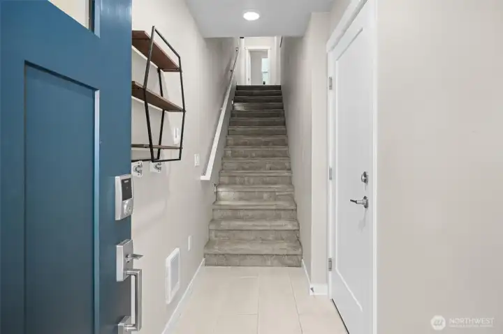 Warm welcoming entry, tile flooring, with door to tandem garage and stairs to main level.