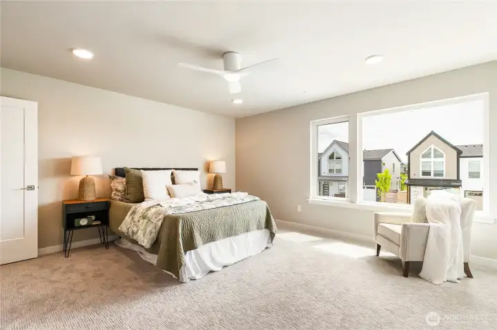 Primary bedroom with large windows, ceiling fan, walk-in closet & ensuite