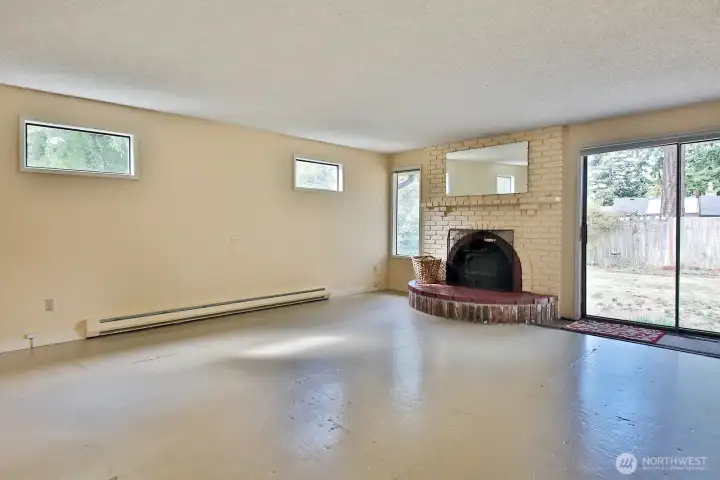 Spacious living room with sliding glass doors to the backyard. Wood stove! Subfloor is painted. Your back is to the hallway and the dining area is beyond the left edge of this photo.