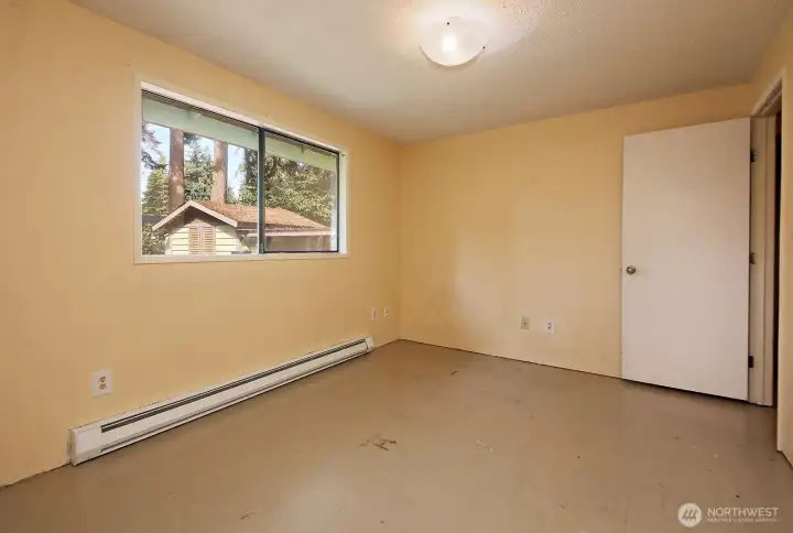 View of Primary Bedroom with your back to the bathroom. You can see the garden shed through the window.