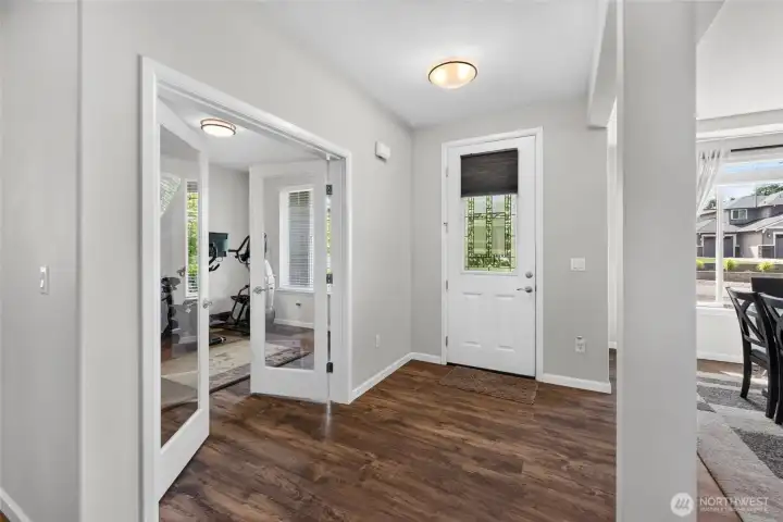 Welcoming entryway with beautiful flooring and glass French doors leading to the versatile fitness room or home office.
