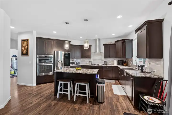 Chef-inspired kitchen features rich cabinetry, granite countertops, stainless steel appliances, gas cooktop, and a large center island perfect for gathering.