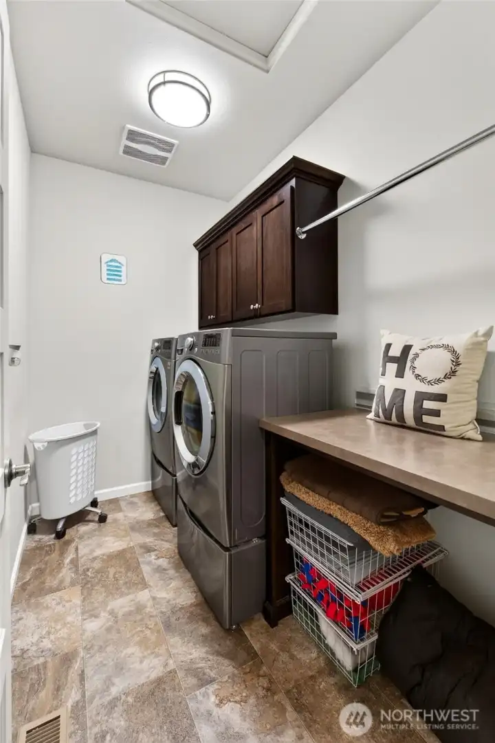 Spacious utility room features upper cabinetry, folding counter, and abundant storage to keep daily chores organized and efficient.