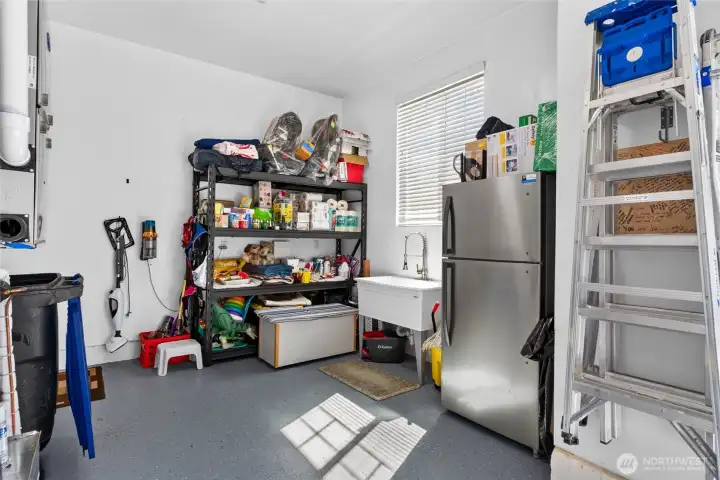 Garage includes additional storage space, utility sink, refrigerator area, and flexible workspace for projects and organization.