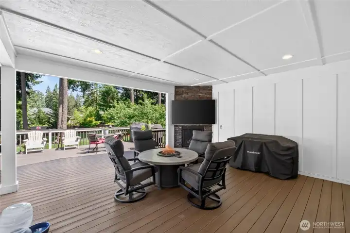 Covered patio features an inviting gathering space with fireplace and TV hookup for year-round enjoyment.
