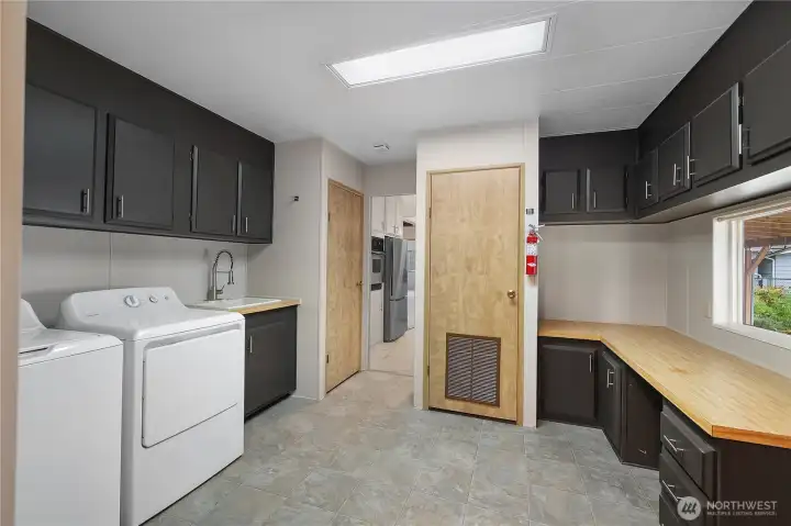 Large laundry space directly off kitchen with tons of storage, folding counter, deep basin sink - washer and dryer brand new and stay!