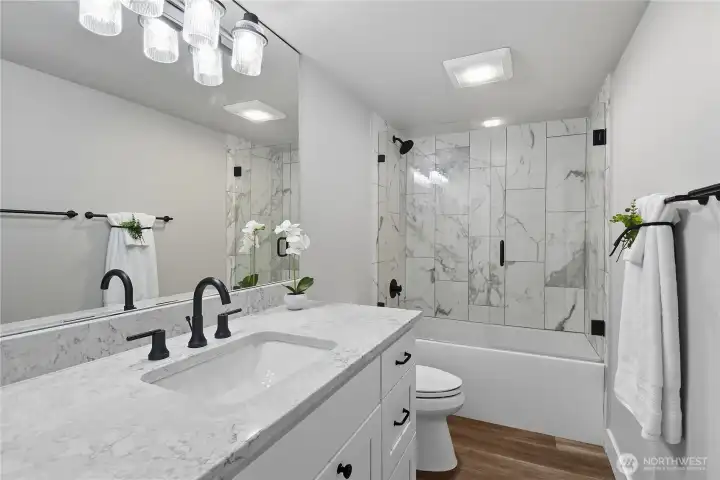 Remodeled hall bath with glass enclosed tub/shower.