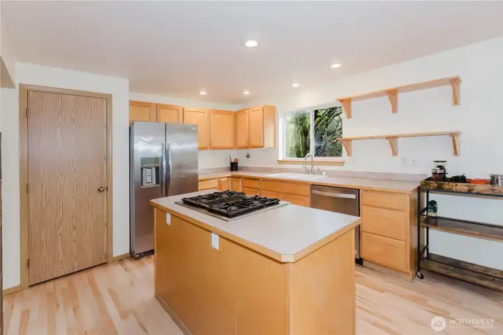This kitchen features a center island with cooktop, a pantry for added storage, and stainless appliances.